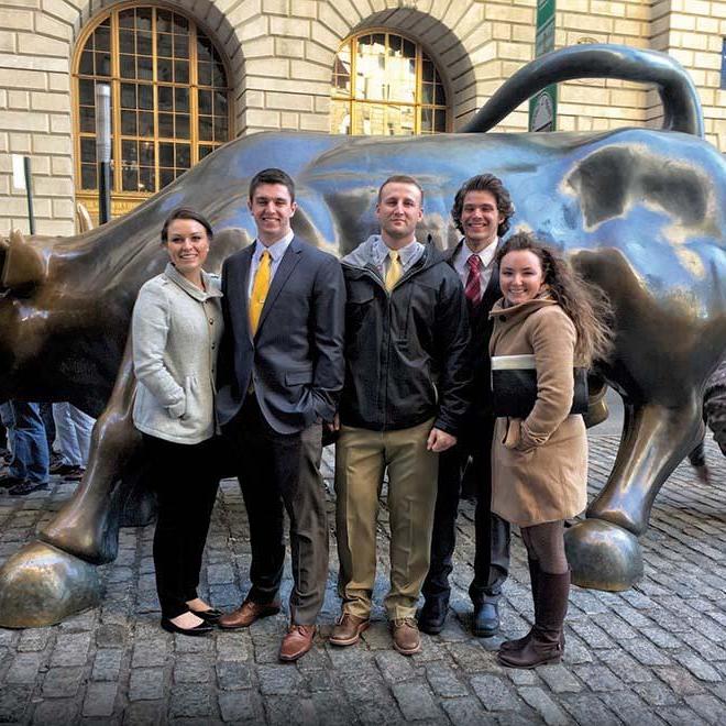 Group of investment club students in front of the Charging Bull in New York City